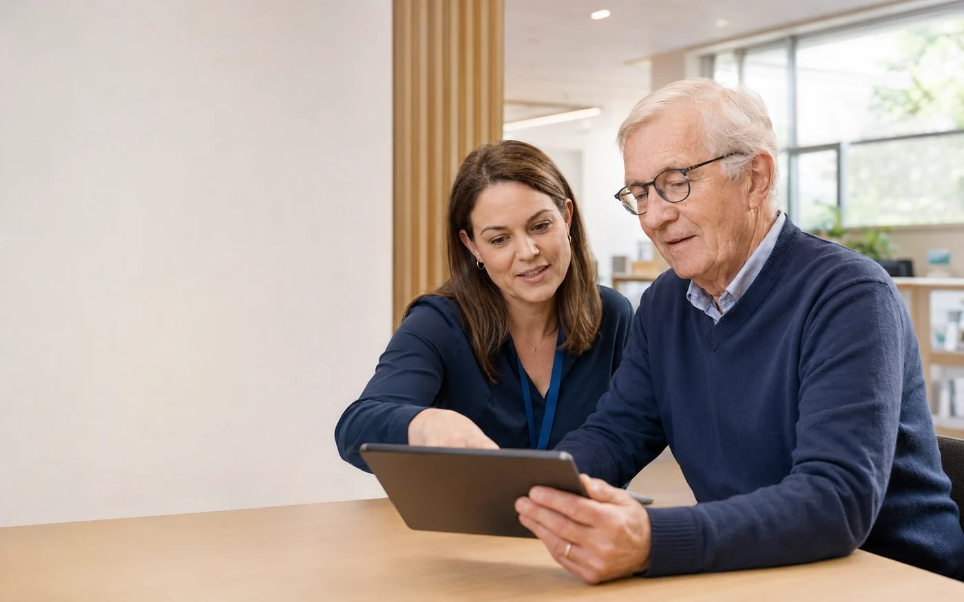Un senior utilise une tablette avec l’aide d’une accompagnatrice